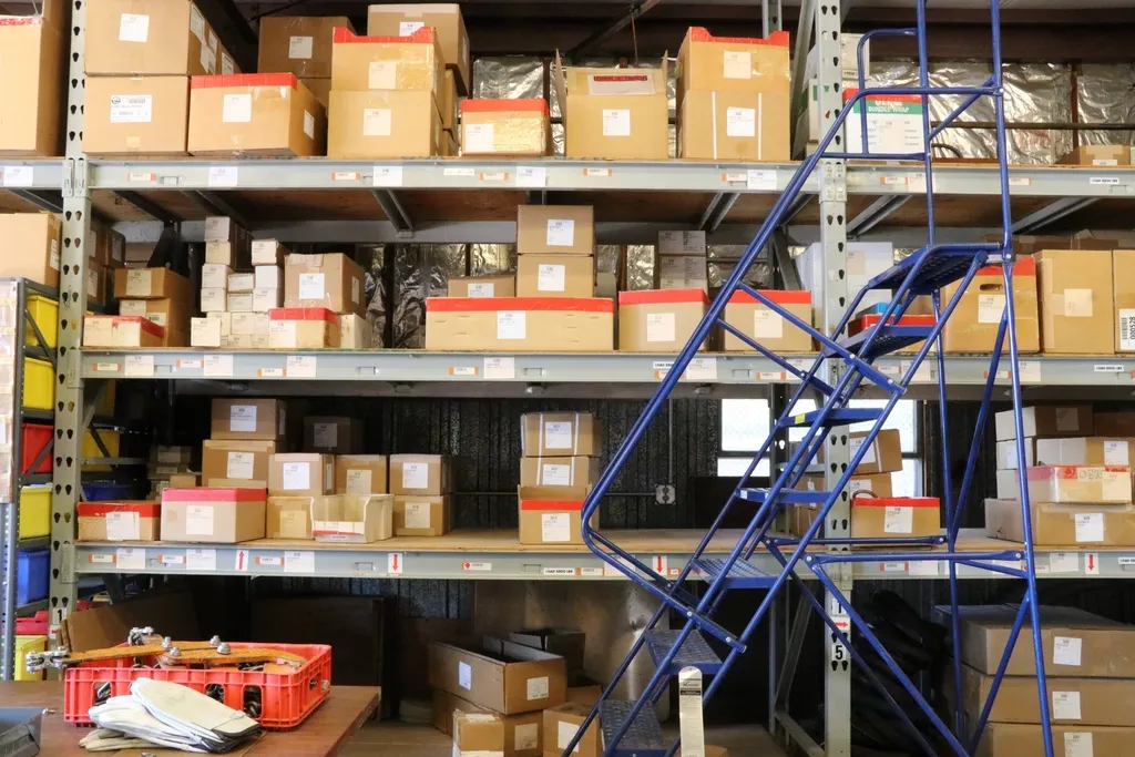 Stockroom shelves filled with boxed goods beside a rolling ladder